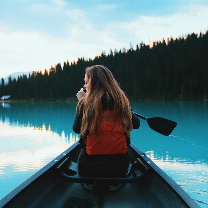 Woman paddling a canoe across a still lake